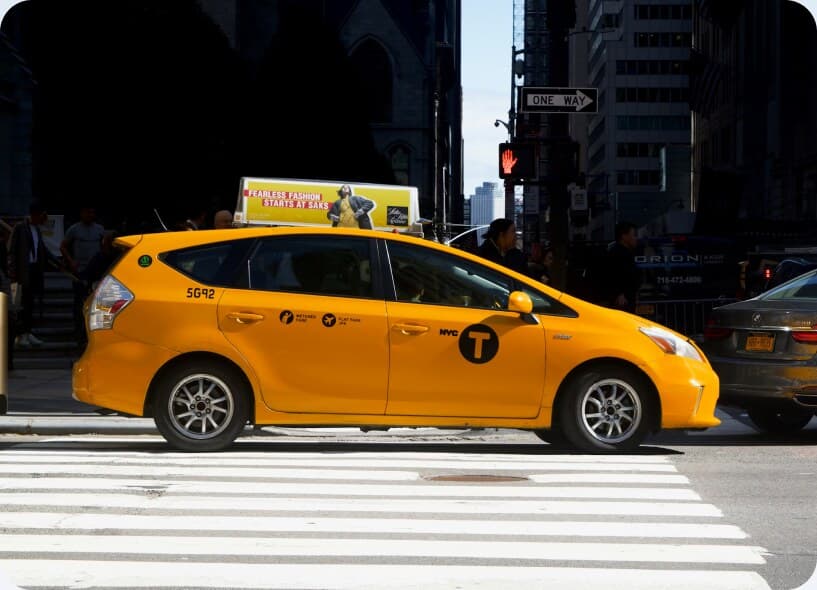 A yellow taxi crossing a city street.